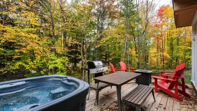 a hot tub on a deck with a picnic table and chairs at Sutton Wellness Cabin #265 unité du haut in Sutton