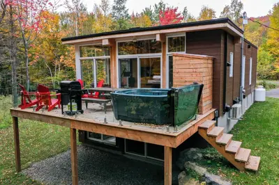 a tiny house on a wooden platform with a hot tub at Sutton Wellness Cabin #265 unité du haut in Sutton