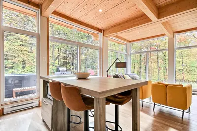 a dining room with a table and chairs and windows at Sutton Wellness Cabin #265 unité du haut in Sutton