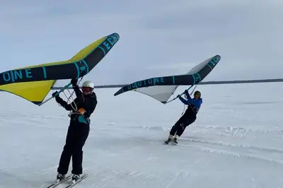 two people on skis holding up a plane in the snow at Chalets Multivoile 4 Saisons in Trois-Rivières