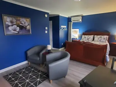 a bedroom with blue walls and a chair and a bed at Dans Les Bras de Memphré in Magog-Orford