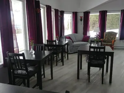 a living room with tables and chairs and a couch at Dans Les Bras de Memphré in Magog-Orford