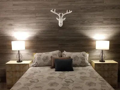 a bedroom with a bed with two lamps and a deer head on the wall at Dans Les Bras de Memphré in Magog-Orford