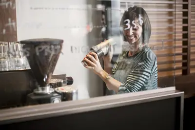 a woman standing behind a window holding a hair dryer at Hôtel Alt Montréal in Montréal