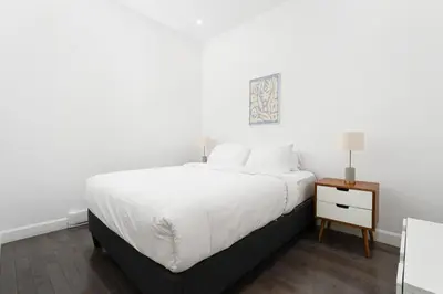 a white bedroom with a bed and a night stand at Boutique Lofts Notre Dame - Vieux Montréal in Montréal