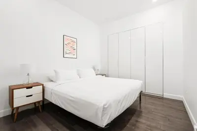 a white bedroom with a white bed and a night stand at Boutique Lofts Notre Dame - Vieux Montréal in Montréal