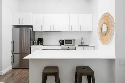 a kitchen with white cabinets and a counter with stools at Boutique Lofts Notre Dame - Vieux Montréal in Montréal