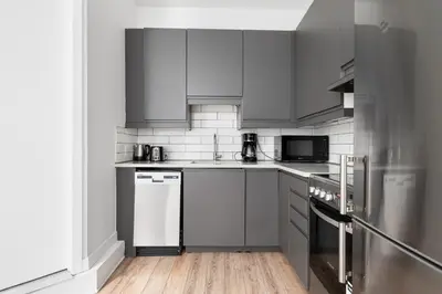 a kitchen with gray cabinets and white appliances at Boutique Lofts Notre Dame - Vieux Montréal in Montréal