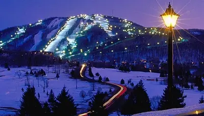 a street light in the snow at night with a mountain at Condo Le Champlain - 105 in Bromont