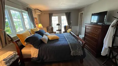 a bedroom with a bed and a tv and windows at Gîte du Caméléon in Sherbrooke