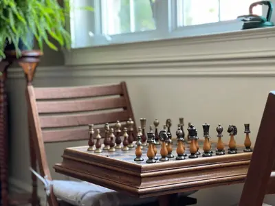 a wooden chess set on a table with a chair at Gîte du Caméléon in Sherbrooke