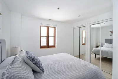a white bedroom with a bed and a mirror at Le Nomade MTL in Montréal