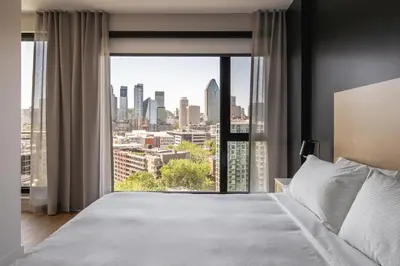 a bedroom with a large window with a city view at Griffintown Hôtel in Montréal