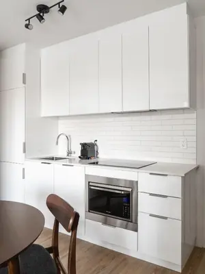 a white kitchen with a sink and a microwave at Griffintown Hôtel in Montréal