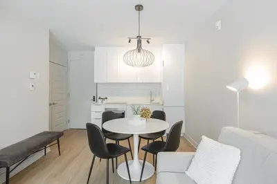 a white living room with a table and chairs at Griffintown Hôtel in Montréal