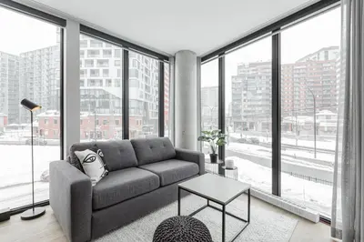 a living room with a couch and large windows at Griffintown Hôtel in Montréal