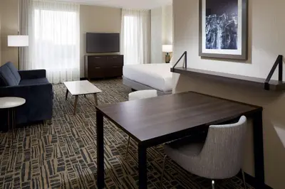 a hotel room with a bed and a table and chairs at Homewood Suites By Hilton Montreal Midtown in Montréal
