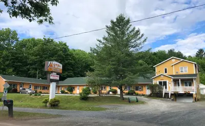 a motel sign in front of a yellow building at Motel de la montagne Orford in Orford