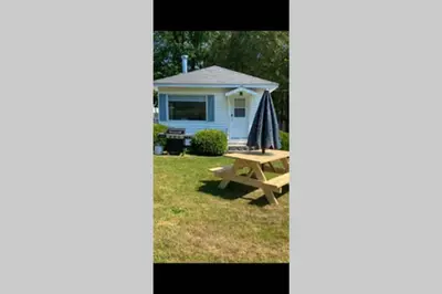 a picnic table in front of a blue house at Chalets Memphrémagog in Magog-Orford