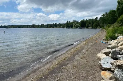 a beach with rocks and water and trees at Chalets Memphrémagog in Magog-Orford