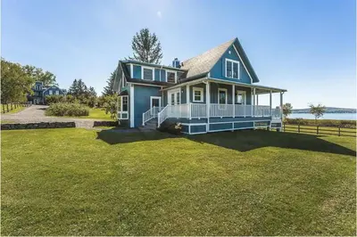 a blue house with a large yard at North House - Lovely Lac-Brome 3 Bedroom Lakefront Cottage in Lac-Brome