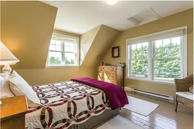 a bedroom with a bed and two windows at North House - Lovely Lac-Brome 3 Bedroom Lakefront Cottage in Lac-Brome