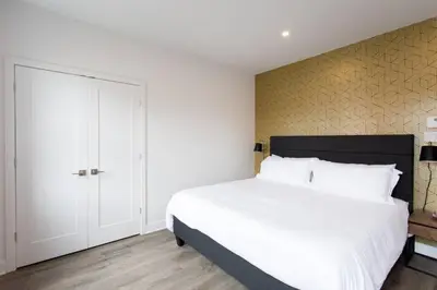 a bedroom with a white bed and a yellow wall at Live Like a Local in this Superb Loft by Den Stays in Montréal