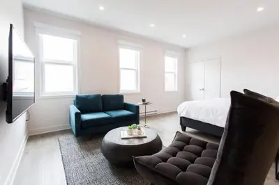 a bedroom with a bed and a couch and a chair at Live Like a Local in this Superb Loft by Den Stays in Montréal