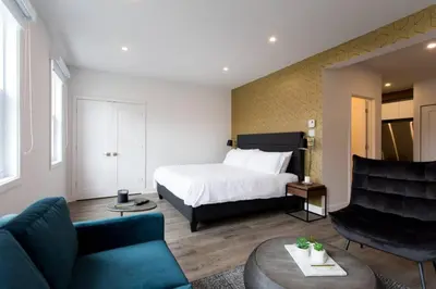 a hotel room with a bed and a couch and chairs at Live Like a Local in this Superb Loft by Den Stays in Montréal