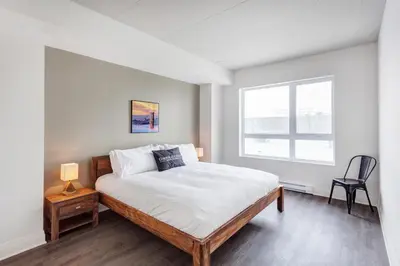 a bedroom with a large bed and a window at L'Equinox Modern Apartments by Corporate Stays in Laval