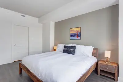 a bedroom with a large bed with white sheets at L'Equinox Modern Apartments by Corporate Stays in Laval