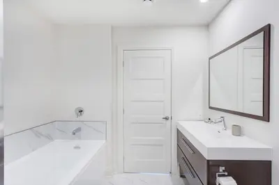 a white bathroom with two sinks and a mirror at L'Equinox Modern Apartments by Corporate Stays in Laval