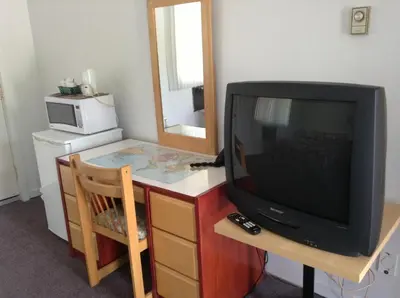 a television sitting on a dresser with a mirror at Motel St-Thomas in Joliette