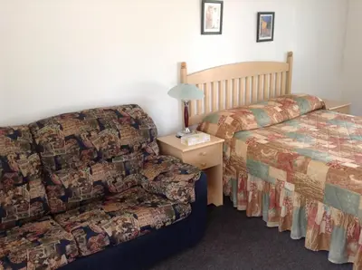 a room with a bed and a couch and a chair at Motel St-Thomas in Joliette
