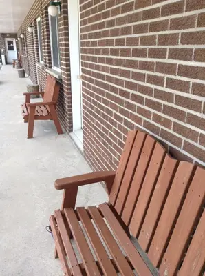 two wooden benches sitting next to a brick wall at Motel St-Thomas in Joliette
