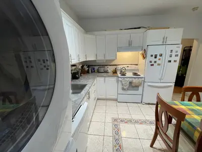 a kitchen with white cabinets and a table and a counter at Chambres EL MEDITERRANEO Rooms in Montréal