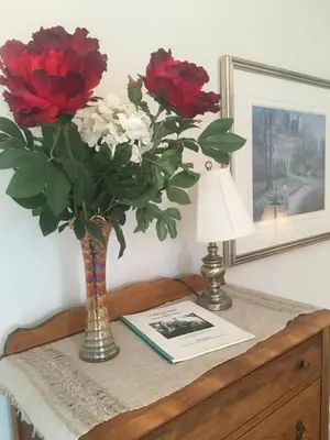 a table with a vase with red and white flowers at La Belle aux Berges in Saint-Denis-sur-Richelieu