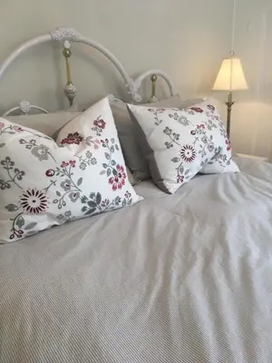a white bed with four pillows on it at La Belle aux Berges in Saint-Denis-sur-Richelieu