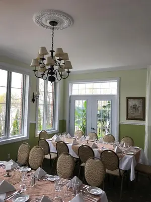 a dining room with tables and chairs and windows at La Belle aux Berges in Saint-Denis-sur-Richelieu