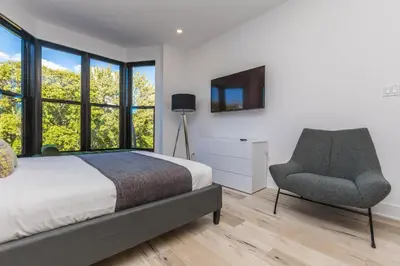 a bedroom with a bed and a chair and windows at Lofts du Parc LaHaie in Montréal