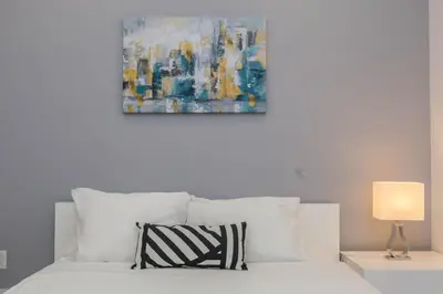 a bedroom with a white bed with a painting on the wall at Lofts du Parc LaHaie in Montréal