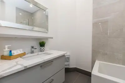 a white bathroom with a sink and a mirror at Lofts du Parc LaHaie in Montréal