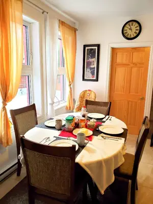 a dining room with a table and chairs and a clock at Maison Montplaisir in Montréal