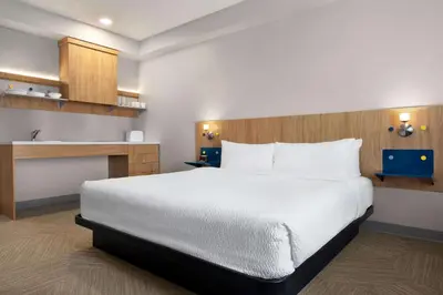 a bedroom with a large white bed and a kitchen at Microtel Inn Suites by Wyndham Lac-Megantic in Lac-Mégantic