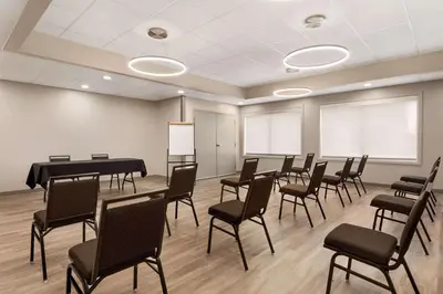 a room with a grand piano and chairs at Microtel Inn Suites by Wyndham Lac-Megantic in Lac-Mégantic