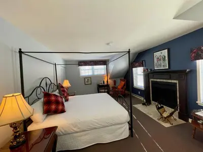 a bedroom with a canopy bed and a fireplace at Auberge Le Tricorne in North Hatley