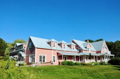 a large house with pink and grey roofs at Auberge Le Tricorne in North Hatley