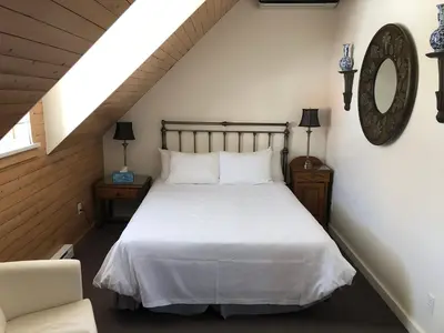 a bedroom with a white bed and a chair at Auberge Le Tricorne in North Hatley
