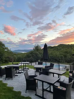 a patio with tables and chairs and an umbrella at Auberge Le Tricorne in North Hatley