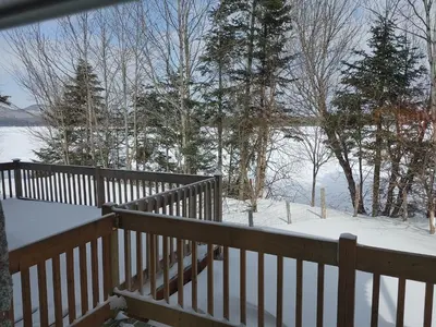 a wooden deck with snow on the ground at La Parade du Huard - Lac et Spa in Saint Sebastien